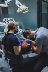 Dental treatment of teeth. A young man at a dentist's appointment. A doctor and an assistant treat a patient's teeth in a dental office