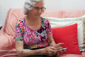 older woman with white hair dialing a number on the mobile phone, loneliness of the elderly,...