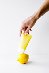 hand holding a cream standing on lemon on white background