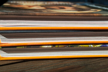 Three books lie on a wooden table. The photo was taken at the wrong angle. A bright light falls on...