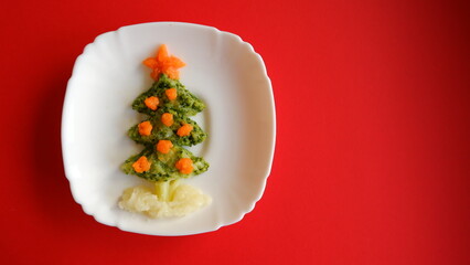 Edible Christmas tree shaped baby vegetable puree on green background for holiday seasonal festive party celebration with healthy food decoration. Cooking step by step