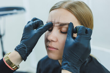 Young woman during professional eyebrow mapping procedure before permanent makeup