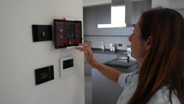 Smart Home Concept. Woman controls home automations touching a tablet in a modern house interior