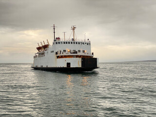Traversier sur l'eau par une journée nuageuse et grise. Ferry arrivant à bon port. Bateau de croisière sur le fleuve près d'une marina Transport des automobiles d'une rive à l'autre.