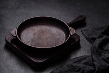 Brown iron empty pan with kitchen utensils on a dark concrete background