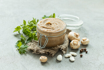 Vegan appetizer. Bean mushroom pate in a glass jar on a linen napkin. Light gray background. Rustic...