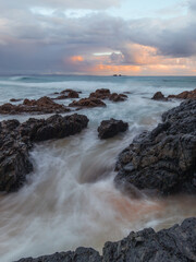 Wave water flowing between rock formation on the coastline.