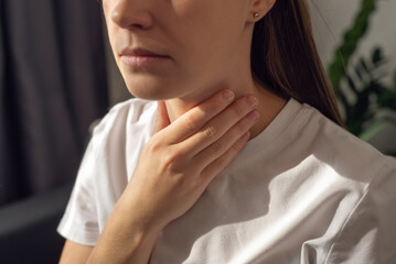 Close-up of unhealthy young caucasian woman touching painful neck, sore throat for flu, cold and infection. Sick upset female feeling bad, unwell, painful swallowing, illness concept