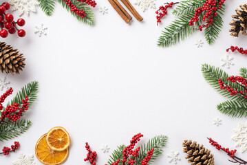 Christmas Eve concept. Top view photo of fir branches in frost mistletoe berries pine cones cinnamon sticks dried orange slices snowflakes on isolated white background with blank space in the middle - obrazy, fototapety, plakaty