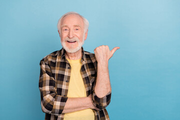 Photo of confident pretty retired man wear plaid shirt pointing thumb empty space isolated blue...