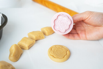 The process of making cookies with shapes in the form of flowers, a rolling pin and a tray, the concept of cooking, baking at home.