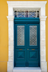 Fototapeta na wymiar Retro style blue wooden front door with metal grates in white stone doorway in yellow wall
