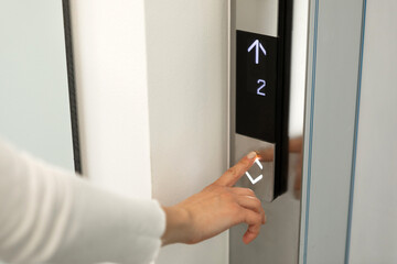 Close-up portrait of female finger pressing elevator button