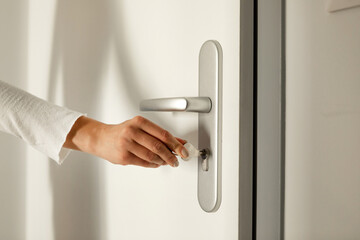 The hand puts the key in the keyhole and opens the door