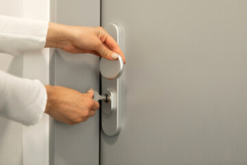 Female hand opens the door with a key to unlock the door