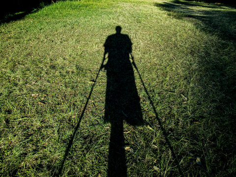 Shadow of a disabled person. Shadow of a person on the green grass.
