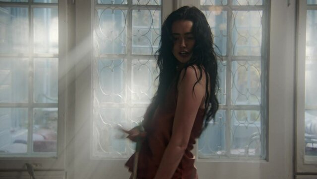 A girl holding a brush and dancing in the corridor, being playful 