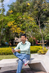 Latin man texting using cellphone in a park in guatemala city
