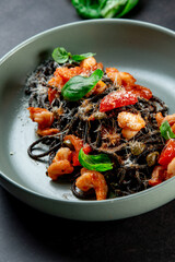 black paste with cuttlefish ink basil ad tomato on blavk background