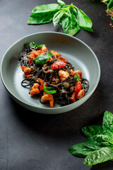 black paste with cuttlefish ink basil ad tomato on blavk background