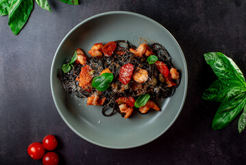 black paste with cuttlefish ink basil ad tomato on blavk background