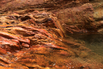 A large layered sedimentary river rock sits on the river Boro-Boro, Southeast Sulawesi, Indonesia.