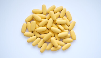 Close-up texture of yellow multivitamin tablets on white background. Healthy lifestyle concept