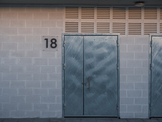 Padlocked metal door of a storage room with the number 18