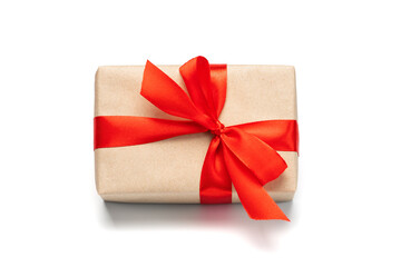 Close up shot of gift box wrapped in craft paper and decorated with red satin ribbon, isolated on white background
