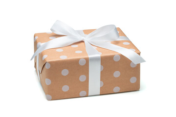 Close up shot of gift box wrapped in dotted craft paper and decorated with satin ribbon bow,...
