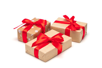 Close up set of three gift boxes wrapped in craft paper and decorated with satin ribbon bows, isolated on white background
