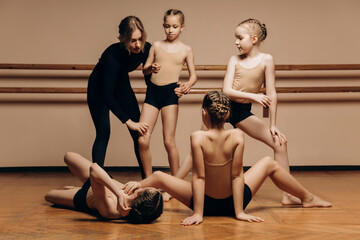 Obraz premium Full-length portrait of a beautiful dance teacher instructing a group of little girls in a dance studio, a space for copying