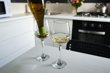 Two glasses of white wine on the kitchen table. Celebrate and enjoy the moment. Tasting of alcoholic beverages. Glass of wine close-up