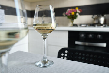 Two glasses of white wine on the kitchen table. Celebrate and enjoy the moment. Tasting of alcoholic beverages. Glass of wine close-up