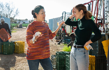 Asian and European women agricultural workers having emotional conversation about job.