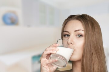 Happy young woman drinking milk at home.