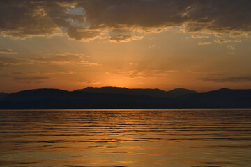 Fototapeta na wymiar Sun is rising from the mountains in Ionian sea.