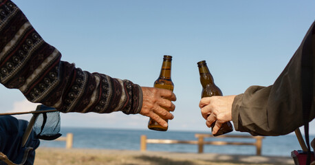 Middle aged or senior people drinking beer.  Two people toasting outdoors. ...