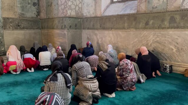 Anonymous muslim women praying on their knees inside Ayasofya mosque in Istanbul, Turkey