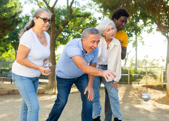 Portrait of friendly mature couples playing petanque at leisure