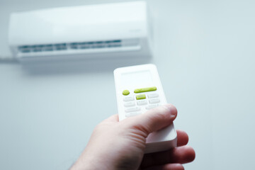 Air conditioner inside the room with man operating remote controller. Air conditioner with remote...