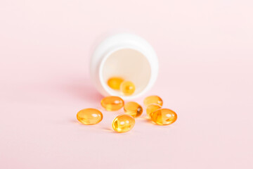 Soft gels pills with Omega-3 oil spilling out of pill bottle close-up. Gel capsules bottle white...