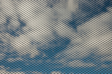 blue background, metal grid in the background blue sky and clouds