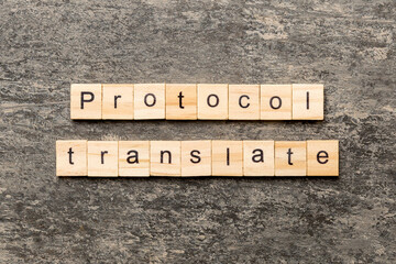 PROTOCOL translate word written on wood block. PROTOCOL translate text on cement table for your desing, concept