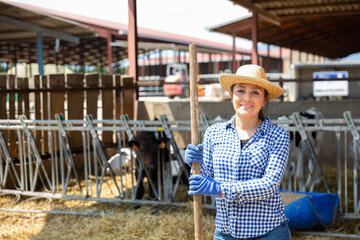 Smiling female proffesional farmer standing near cows at farm