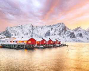 Traditionele Noorse rode houten huizen (rorbuer) aan de oever van Reinefjorden bij het dorp Hamnoy bij zonsondergang.