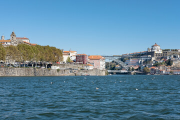 Fototapeta na wymiar Views from Douro River towards the double-deck metal arch bridge known as Dom Luis I which connects the two popular neighborhoods Ribeira and Villa Nova de Gaya in Porto, Portugal