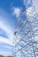 Unidentified worker at height dismantling a scaffolding tower