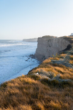 Vertical image of a cliff over the sea at sunset. Photo of the cliffs of Mar del Plata, Argentina, with people in the background.