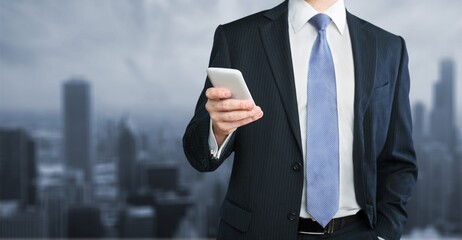 Young business person holding phone in city